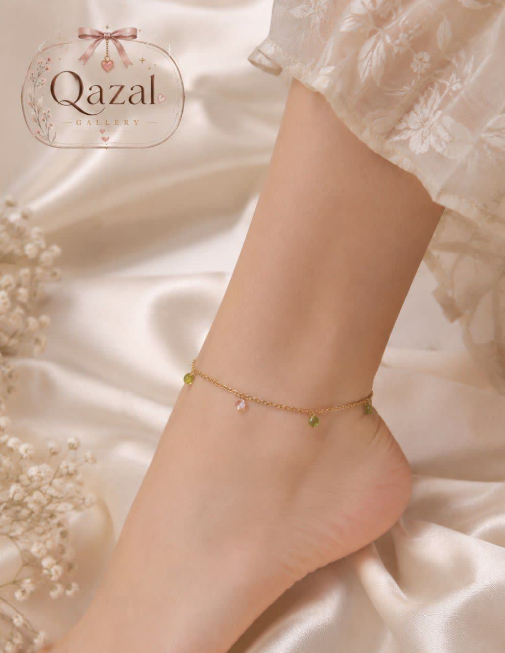 پابند I am زنجیری طلایی با آویزهای سبز و نگین شفاف روی مچ پا